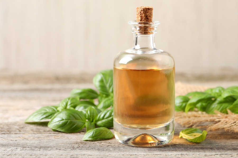 Basilicumolie recept Sfeerbeeld: Een kurken fles is gevuld met olie en omgeven door basilicum